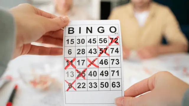 Hands holding bingo cards at a local bingo hall